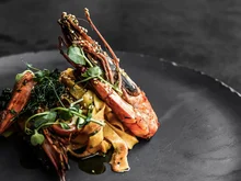 Was erwarten Sie von einer Bar in Ischgl? Garnelen auf Pasta mit grünen Kräutern auf schwarzem Teller