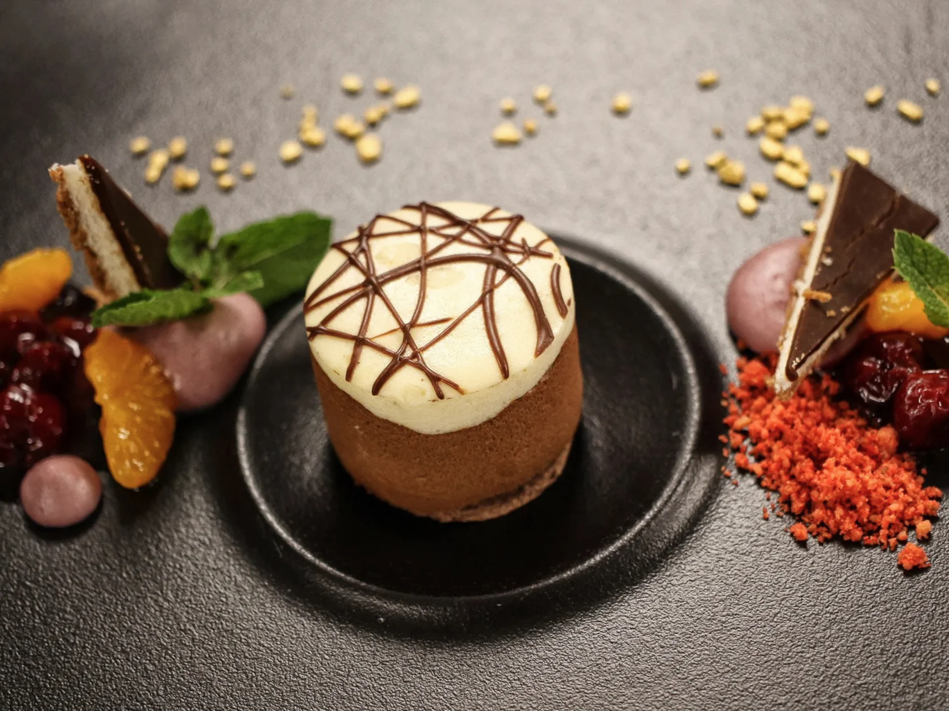 Die Bilder aus dem Hotel Salnerhof Elegantes Dessert mit Schokoladenmousse, Fruchtkompott und Minzblatt auf schwarzem Teller