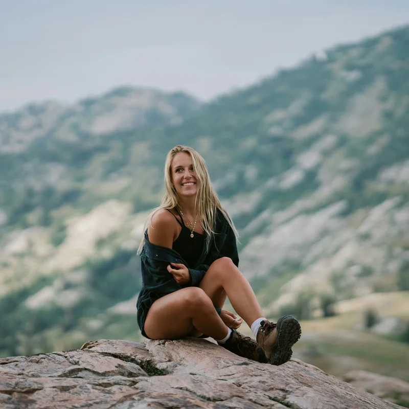 Ischgl Frau sitzt auf Felsen mit Berglandschaft im Hintergrund