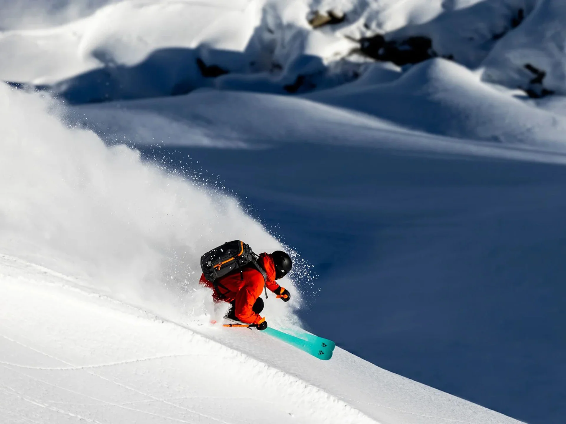 Die Bilder aus dem Hotel Salnerhof Skifahrer in roter Jacke fährt im Tiefschnee an einem sonnigen Berghang