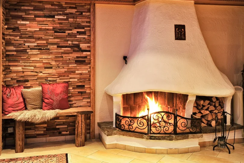 Die Geschichte des Salnerhofs Gemütlicher Kamin mit brennendem Feuer und Holzbänken mit Kissen