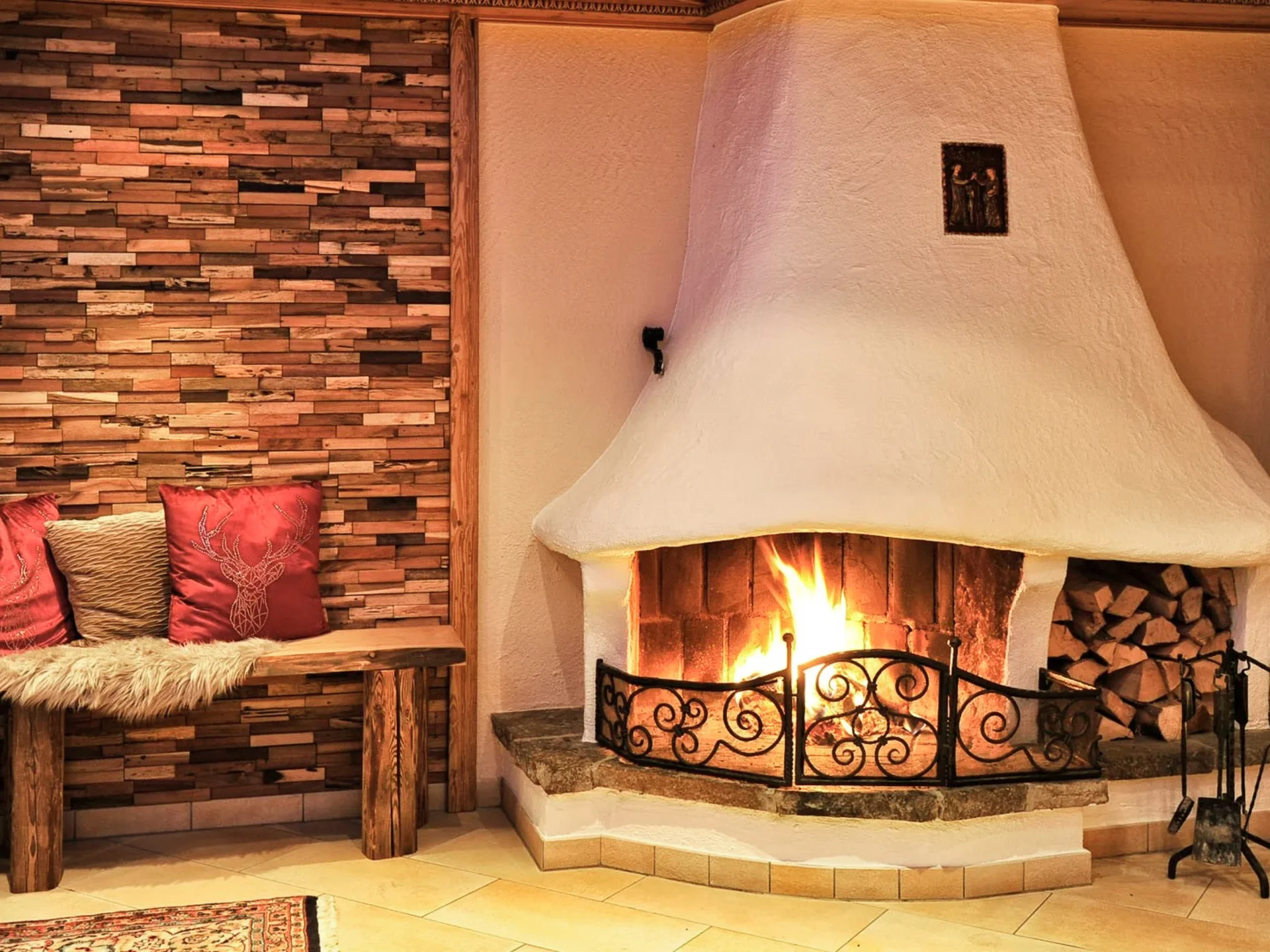 Die Bilder aus dem Hotel Salnerhof Gemütlicher Kamin mit brennendem Feuer und Holzbänken mit Kissen