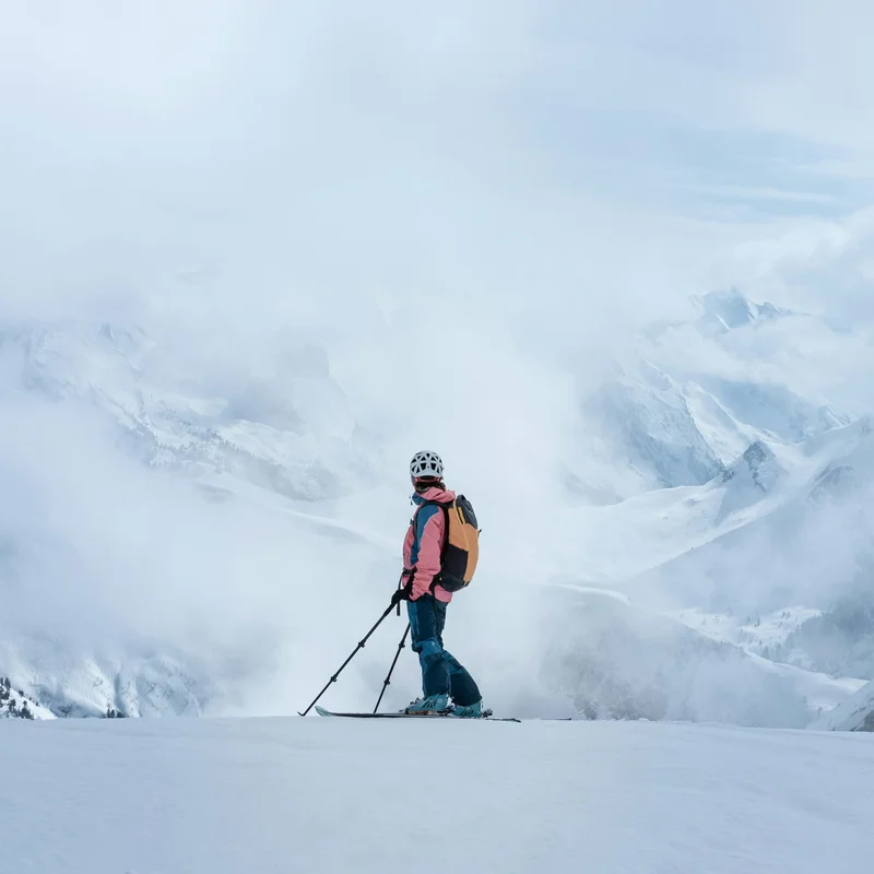Ihr Skihotel in Ischgl Skifahrer mit Helm und Rucksack auf verschneitem Berg vor nebligen Bergen