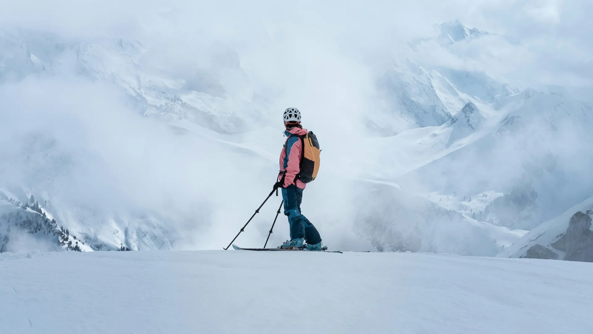Ischgl Skifahrer mit Helm und Rucksack auf verschneitem Berg vor nebligen Bergen