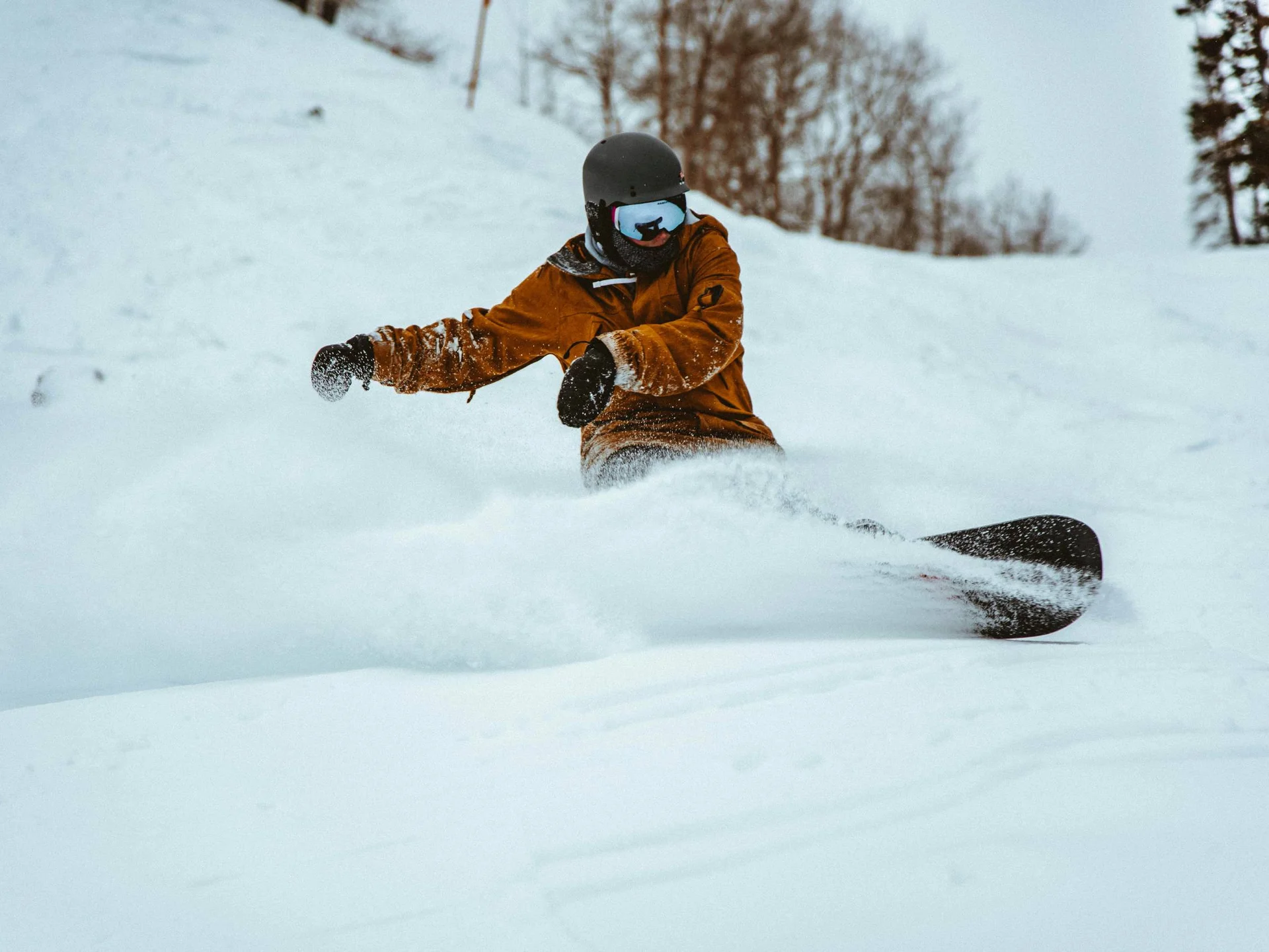 Die Bilder aus dem Hotel Salnerhof Snowboarder in brauner Jacke fährt durch frischen Schnee im Winterwald