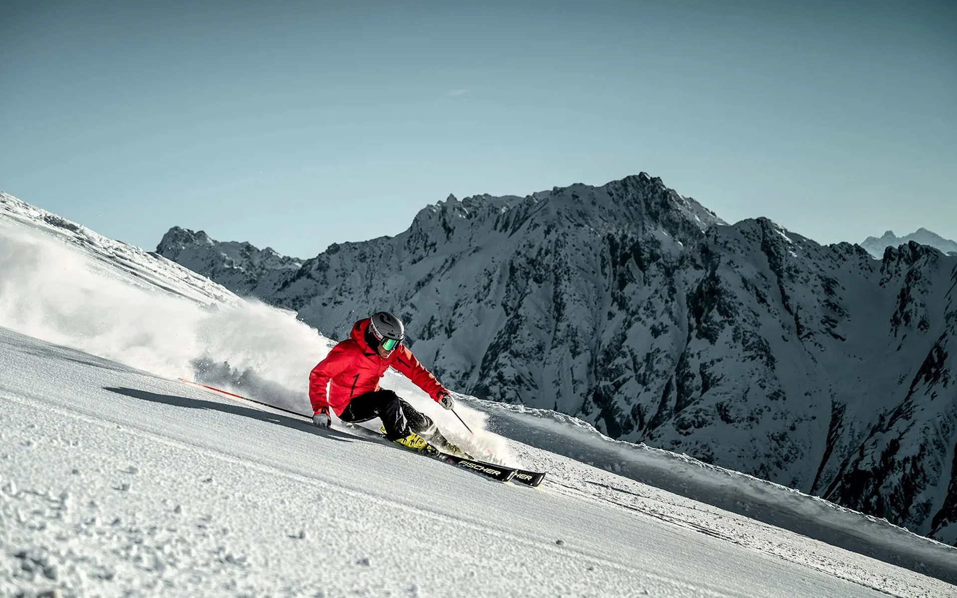 Der Salnerhof – das Hotel in Ischgl Skifahrer in roter Jacke fährt auf schneebedecktem Hang vor Bergkulisse