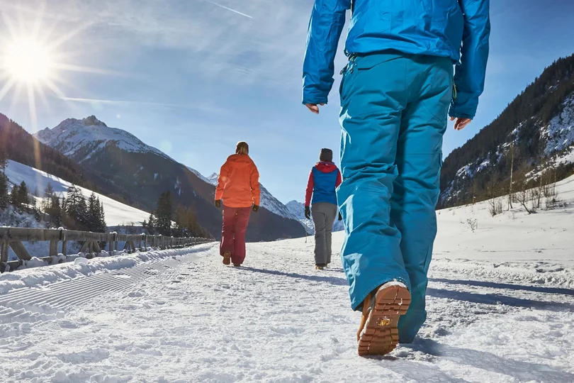 Ihr Skihotel in Ischgl Drei Personen wandern bei Sonnenschein durch verschneite Berglandschaft