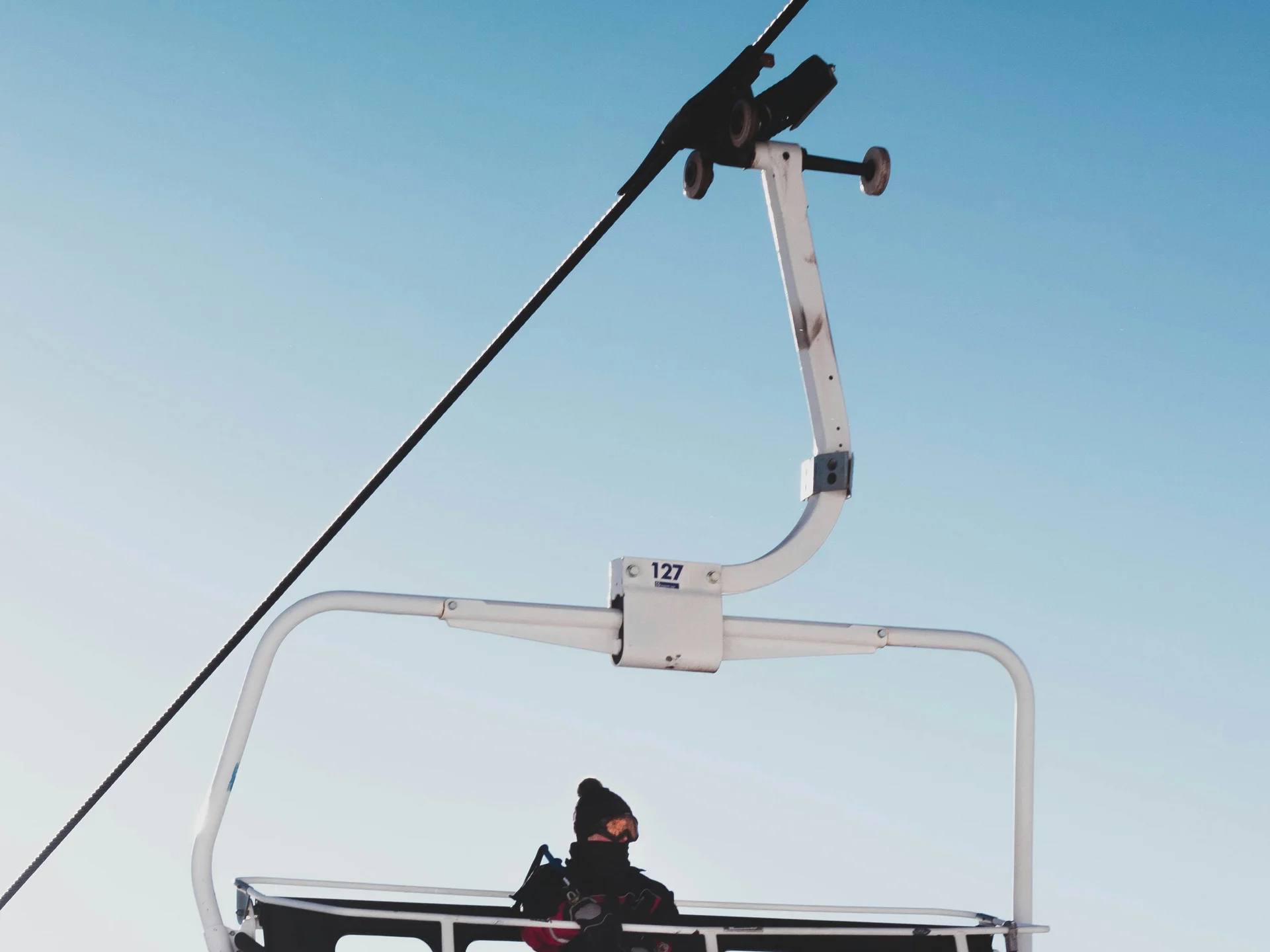 Die Bilder aus dem Hotel Salnerhof Person sitzt auf einem Skilift mit Skiern vor klarem blauem Himmel und Bergkulisse