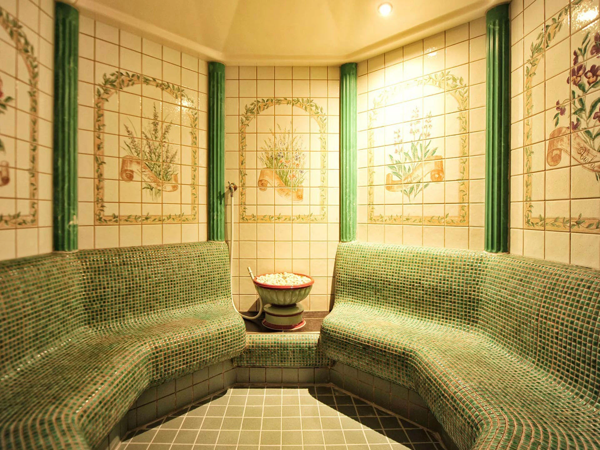 Die Bilder aus dem Hotel Salnerhof Saunaraum mit grünen Mosaikbänken und dekorativen Wandfliesen mit Blumenmotiven