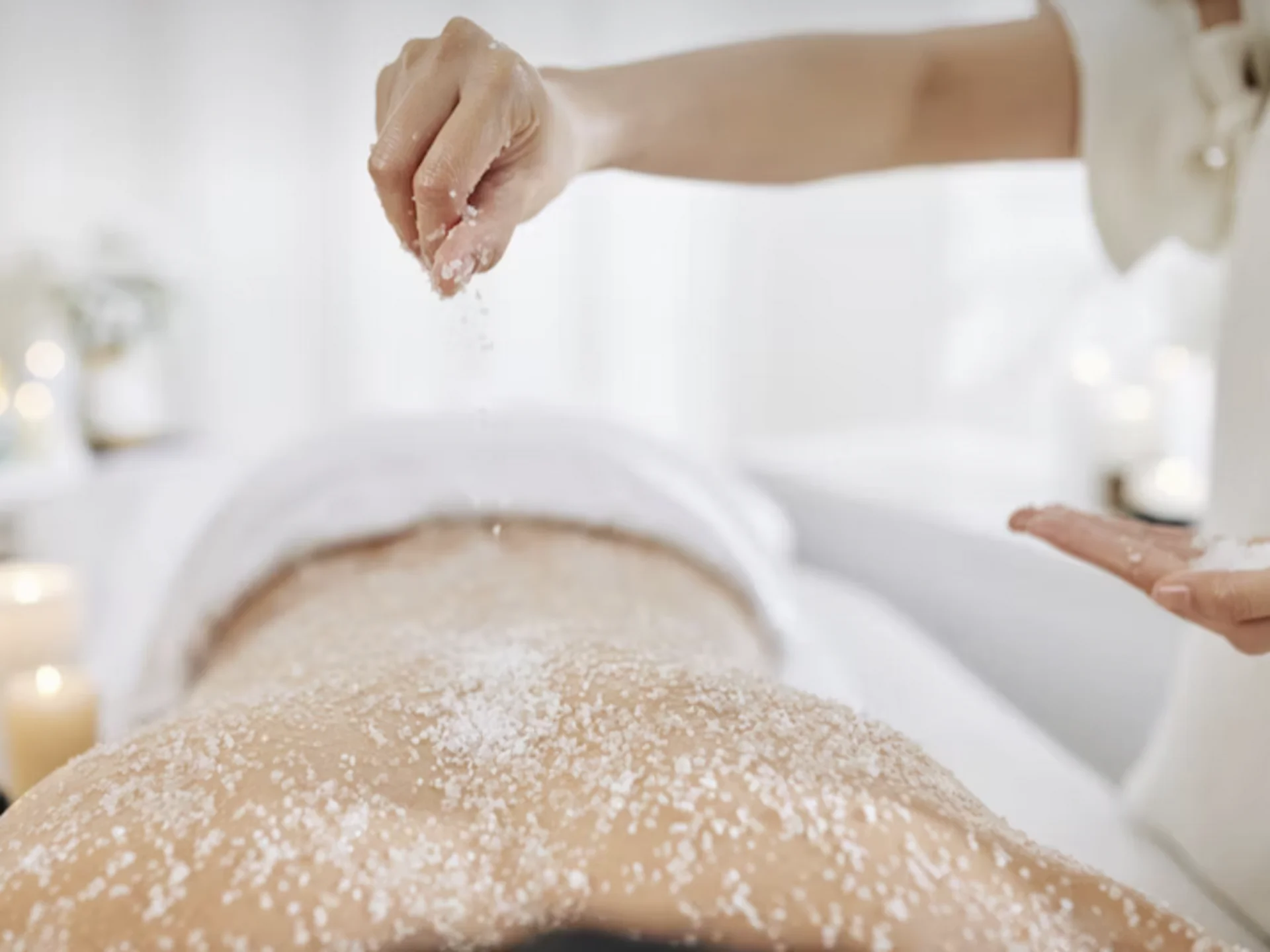 Die Bilder aus dem Hotel Salnerhof Hand streut Salz auf den Rücken einer Person bei einer Wellnessmassage