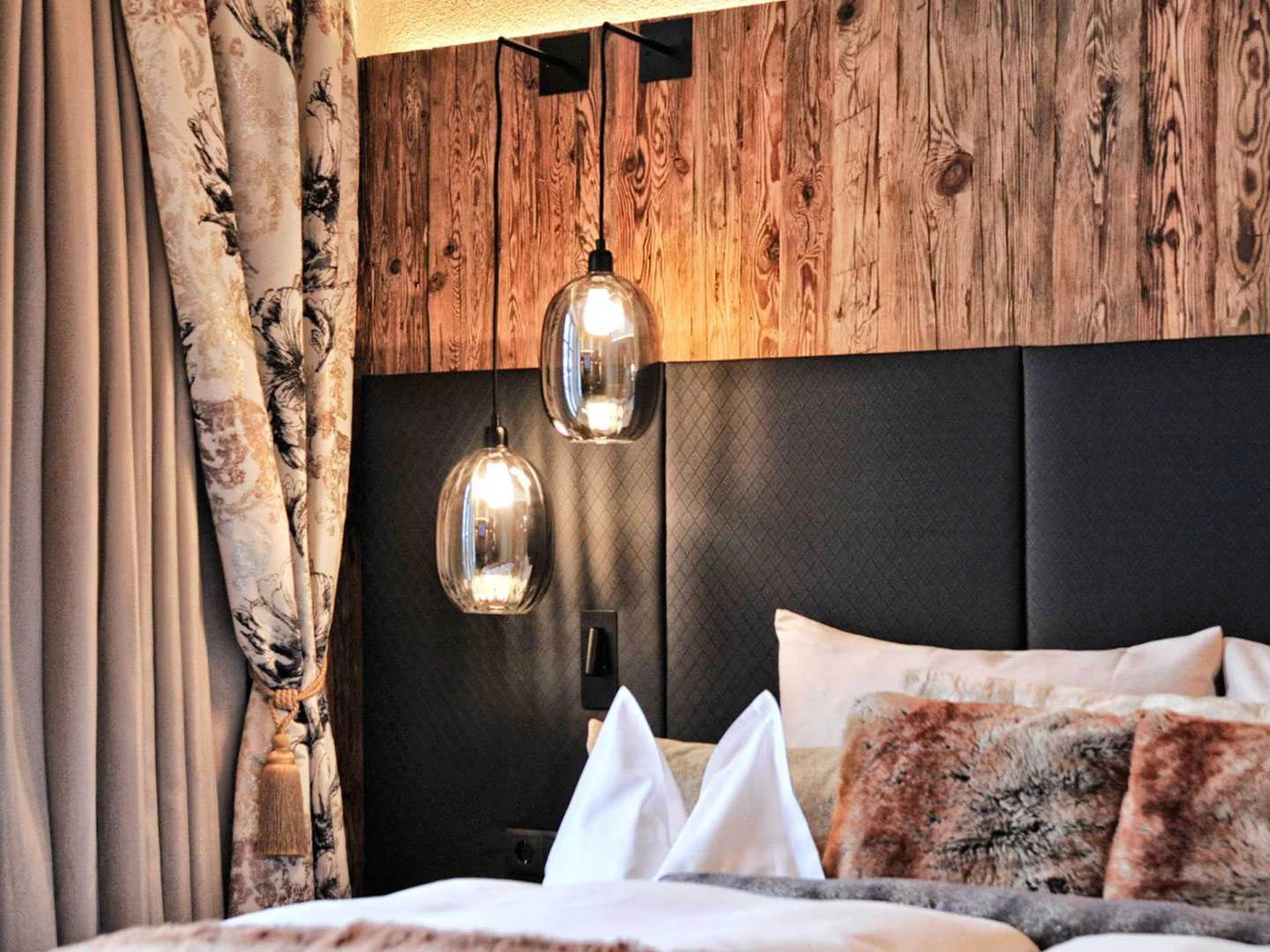 Die Bilder aus dem Hotel Salnerhof Gemütliches Schlafzimmer mit Holzpaneel, Hängelampen und dekorativen Kissen