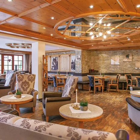 Was erwarten Sie von einer Bar in Ischgl? Gemütlicher Hotel-Lounge-Bereich mit Sesseln, Tischen und Holzbalkendecke