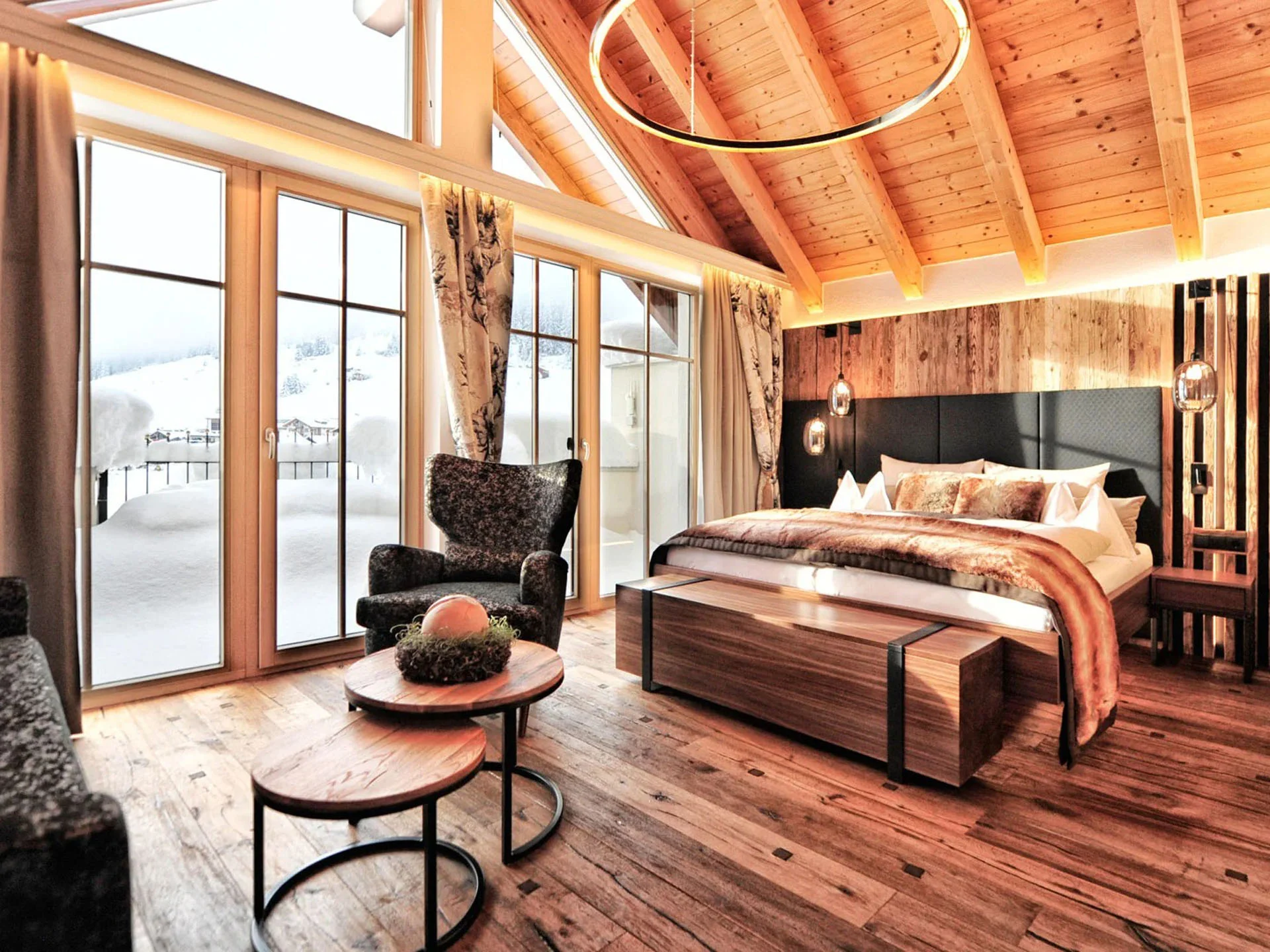 Die Bilder aus dem Hotel Salnerhof Gemütliches Schlafzimmer mit Holzboden und großen Fenstern mit Blick auf Schnee