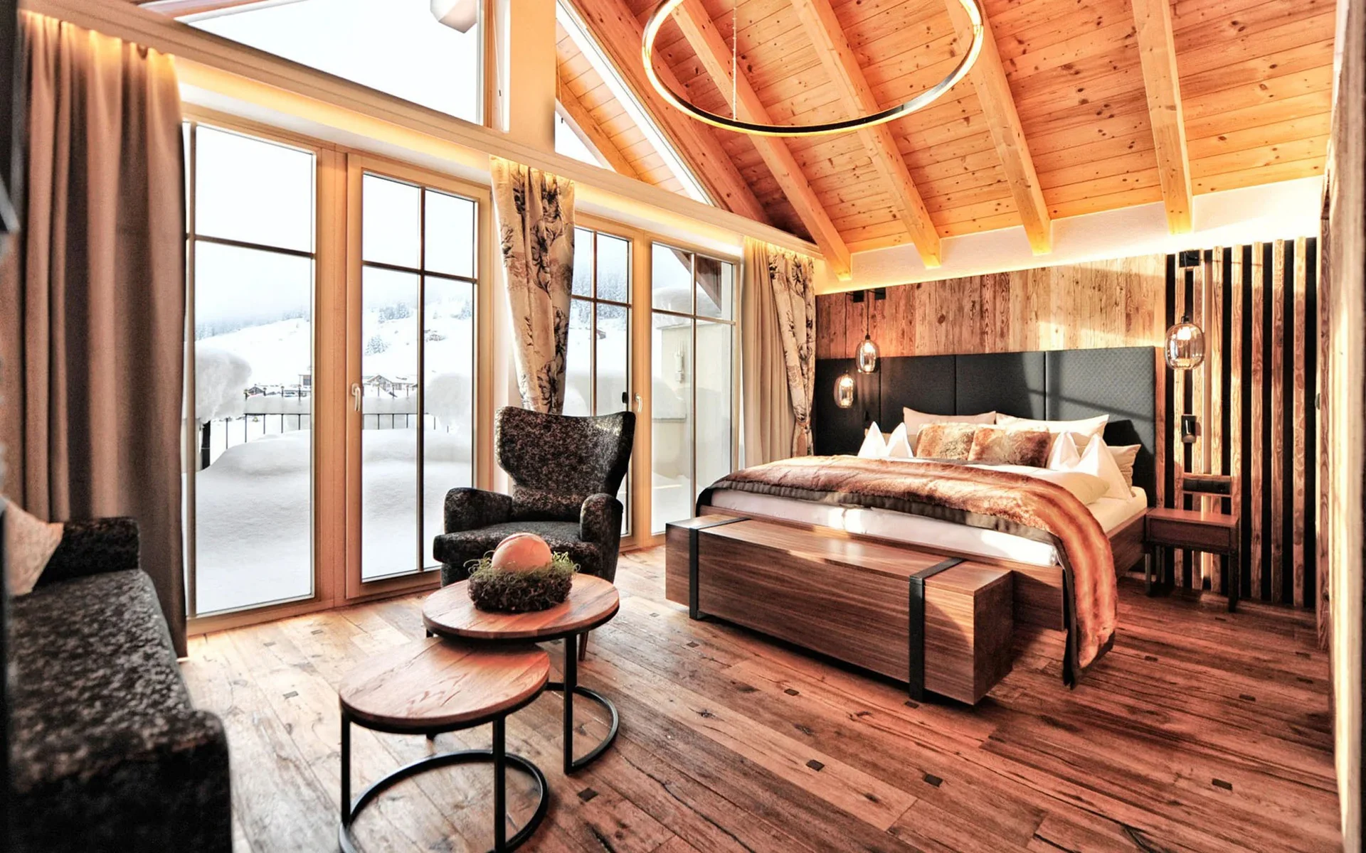 Gemütliches Schlafzimmer mit Holzboden und großen Fenstern mit Blick auf Schnee
