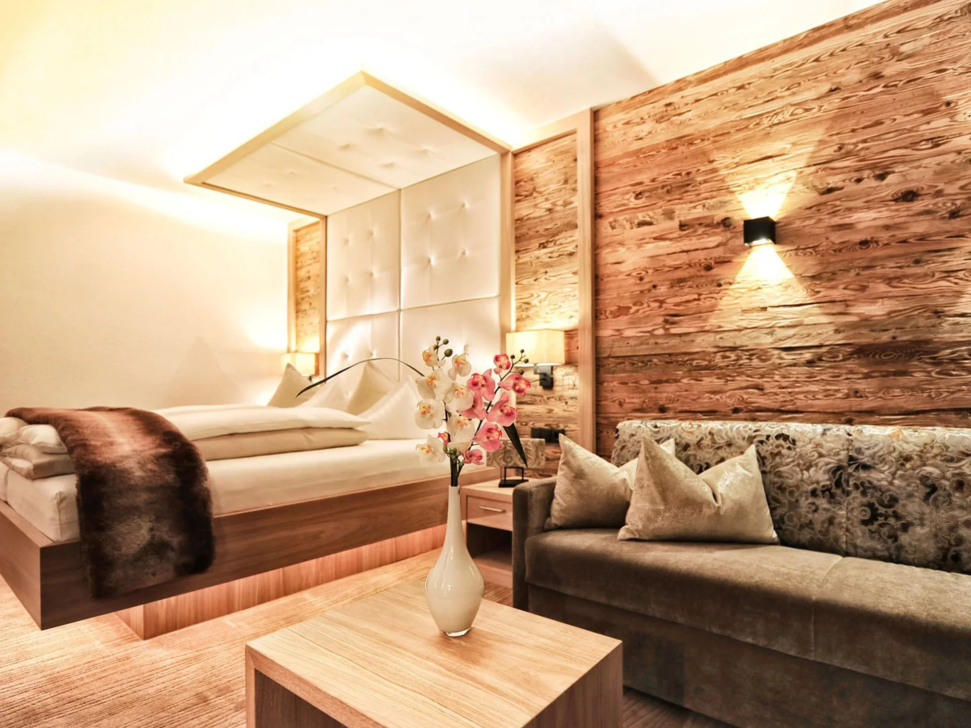 Die Bilder aus dem Hotel Salnerhof Gemütliches Hotelzimmer mit Holzwand, Bett und Sofa