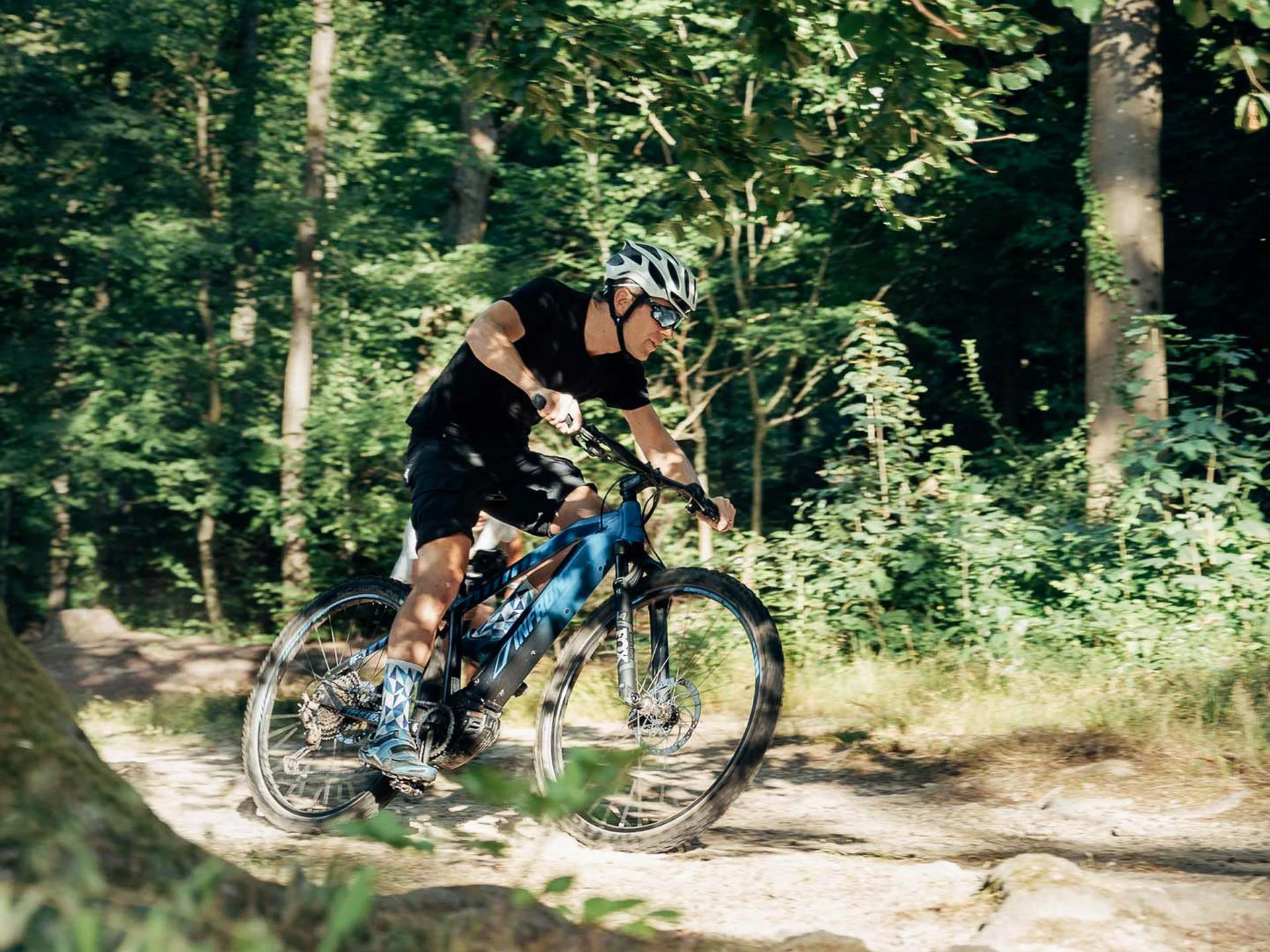 Pictures from Hotel Salnerhof Man riding mountain bike on forest trail in sunny weather