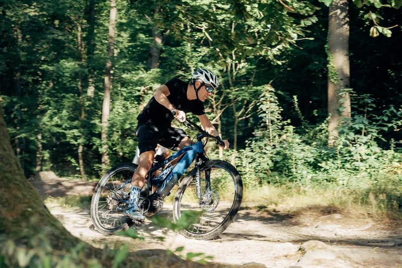 Silvretta Skigebiet Mann fährt Mountainbike auf Waldweg bei sonnigem Wetter