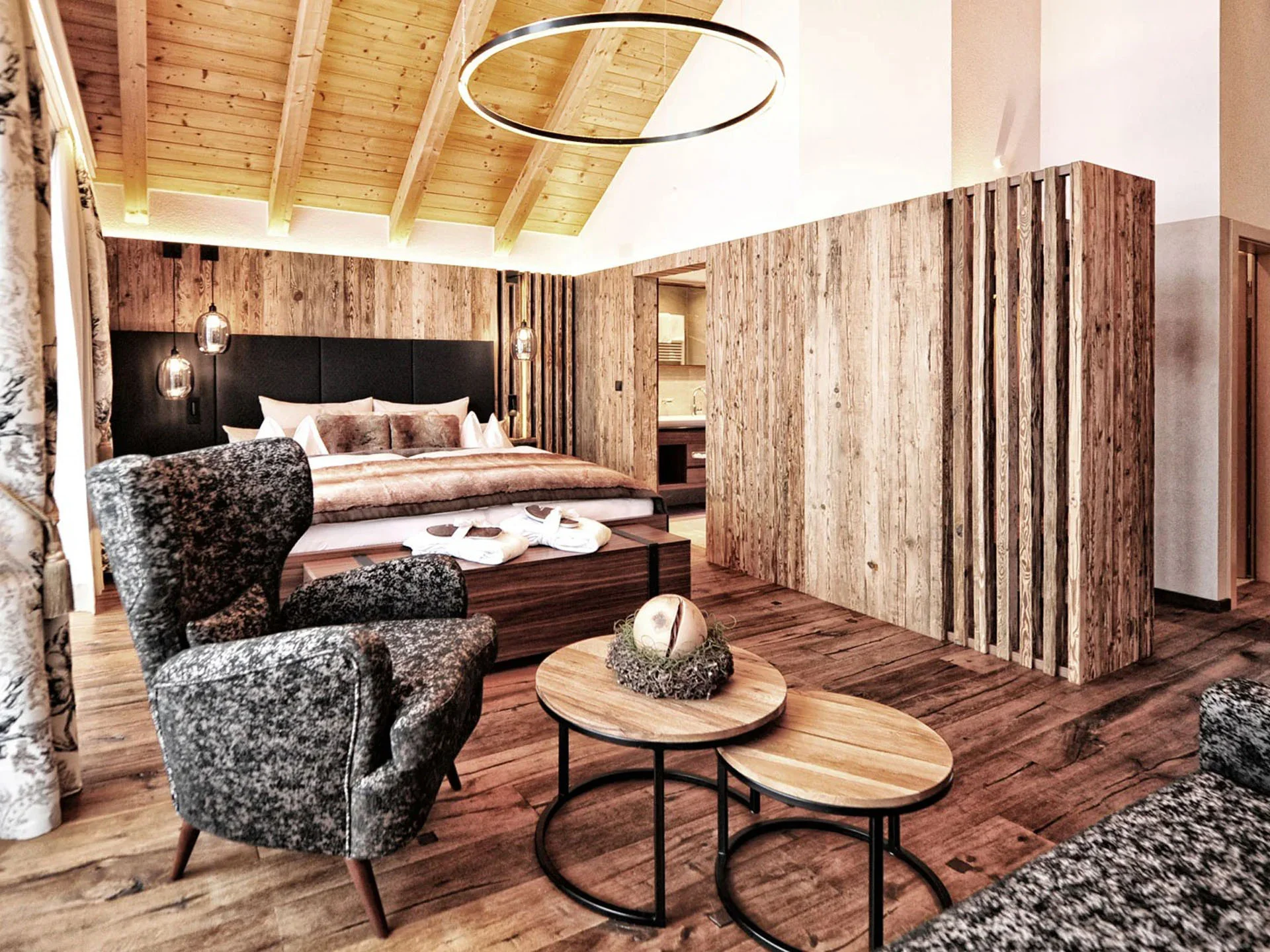 Die Bilder aus dem Hotel Salnerhof Gemütliches Hotelzimmer mit Holzmöbeln, Sessel und Doppelbett unter Holzdecke