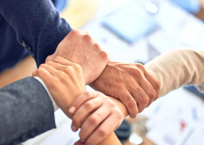 Kellner mit Inkasso Vier Hände greifen sich im Büro zur Teamzusammenarbeit