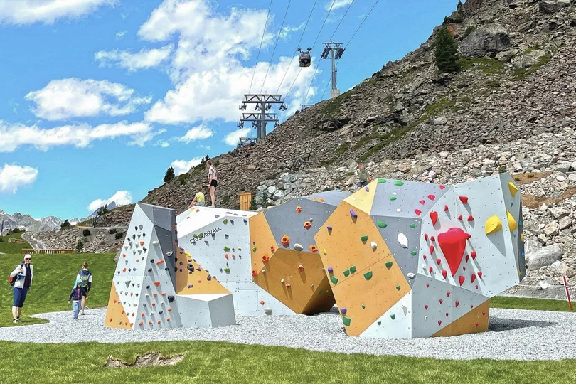 Ihr Sommer im Paznaun im Wander- und Bike-Hotel in Ischgl Boulderwand mit Klettergriffen auf einer Wiese vor Bergkulisse und Seilbahn