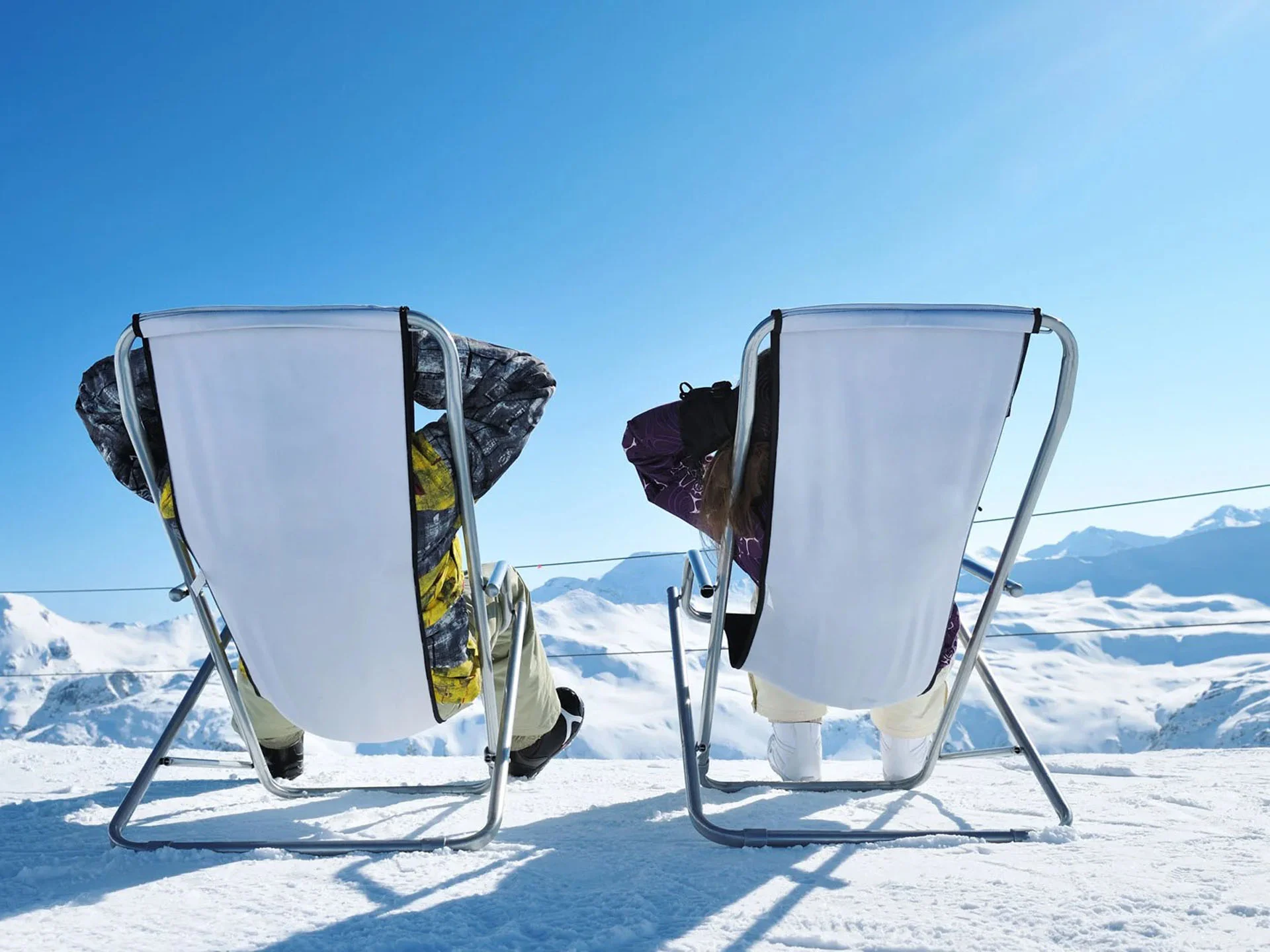 Die Bilder aus dem Hotel Salnerhof Zwei Personen sitzen auf Liegestühlen im Schnee mit Blick auf verschneite Berge