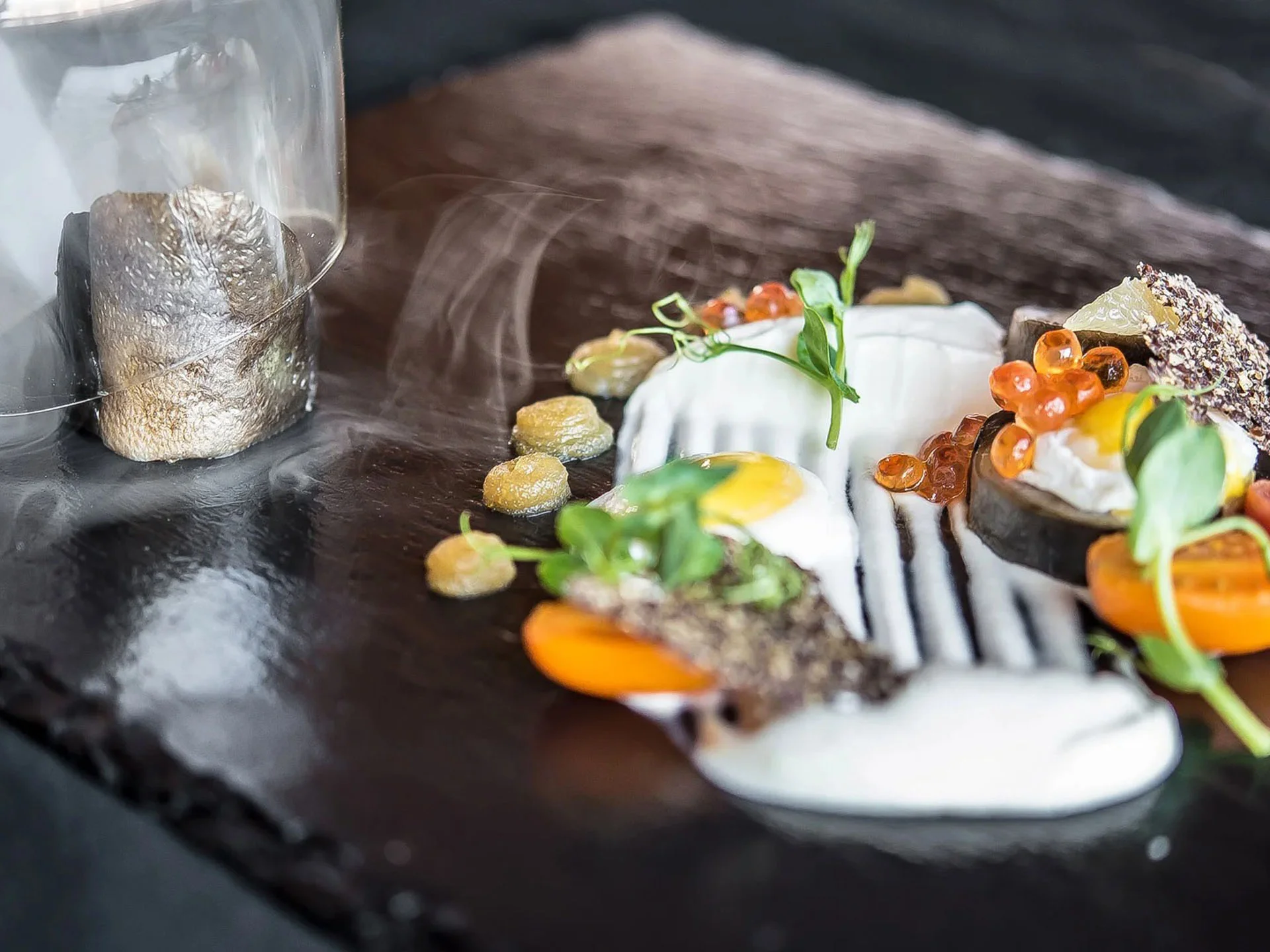 Die Bilder aus dem Hotel Salnerhof Kreativ angerichtetes Gourmetgericht mit Ei, Tomaten und Saucen auf schwarzem Stein