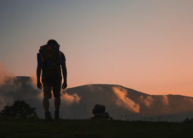 Ihr Sommer im Paznaun im Wander- und Bike-Hotel in Ischgl Wanderer mit Rucksack vor Berglandschaft bei Sonnenuntergang
