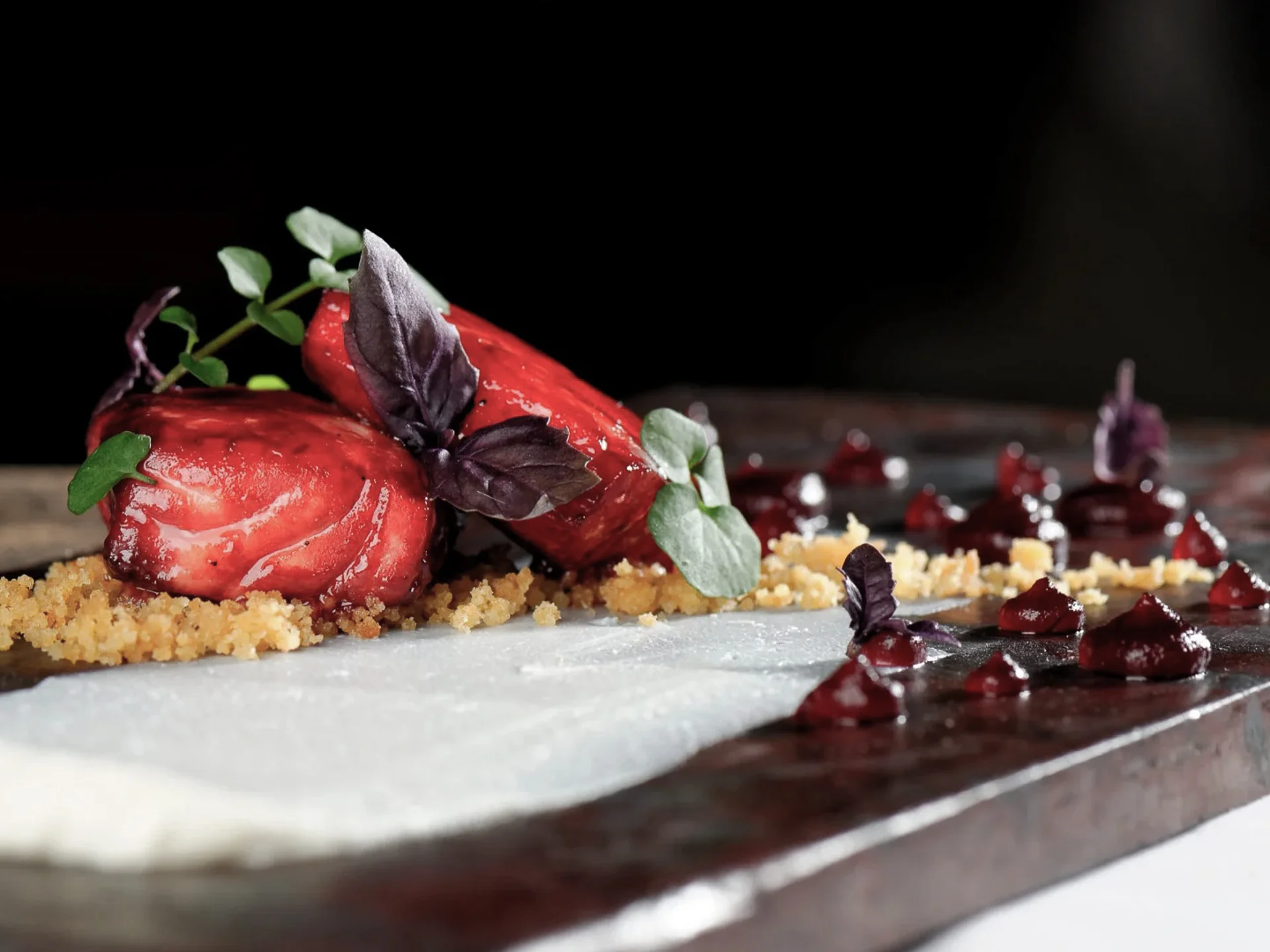 Die Bilder aus dem Hotel Salnerhof Fein angerichtete Gourmet-Vorspeise mit roten Beeren und Kräutern auf schwarzem Teller