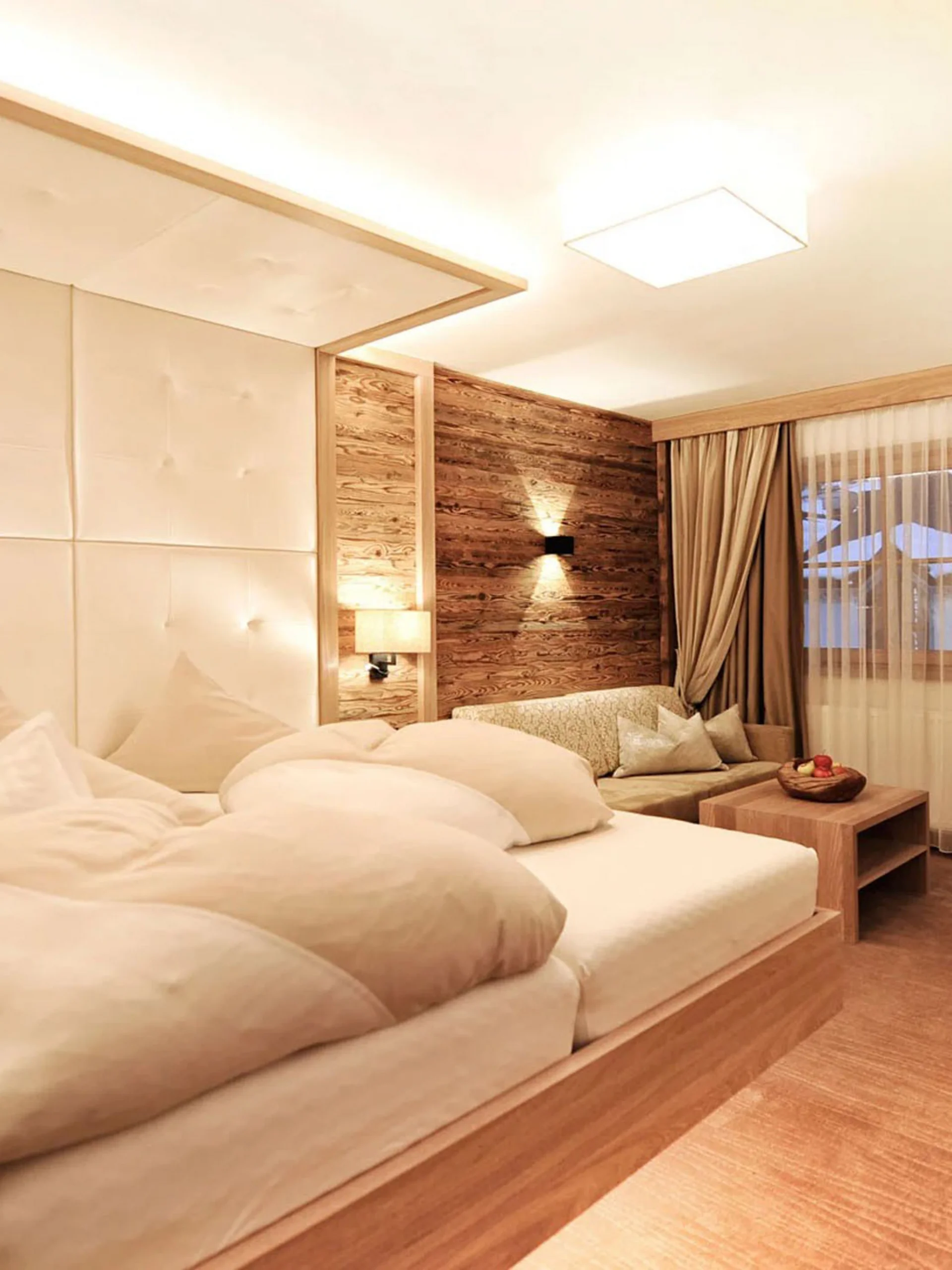 Der Salnerhof – das Hotel in Ischgl Gemütliches Hotelzimmer mit großem Bett, Sofa, Schreibtisch und Vorhängen