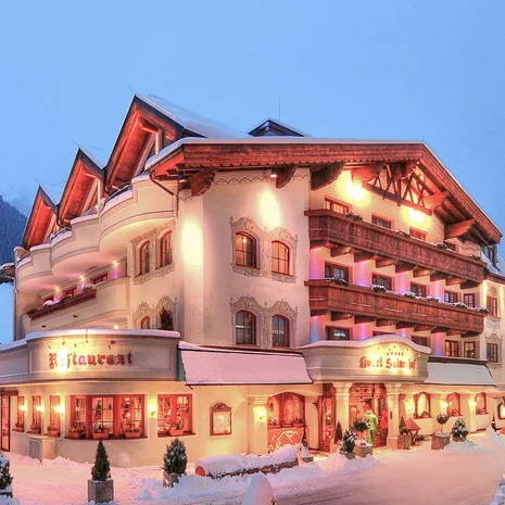 Ihre Anreise zum Salnerhof in Ischgl Beleuchtetes Hotel in verschneiter Berglandschaft bei Dämmerung