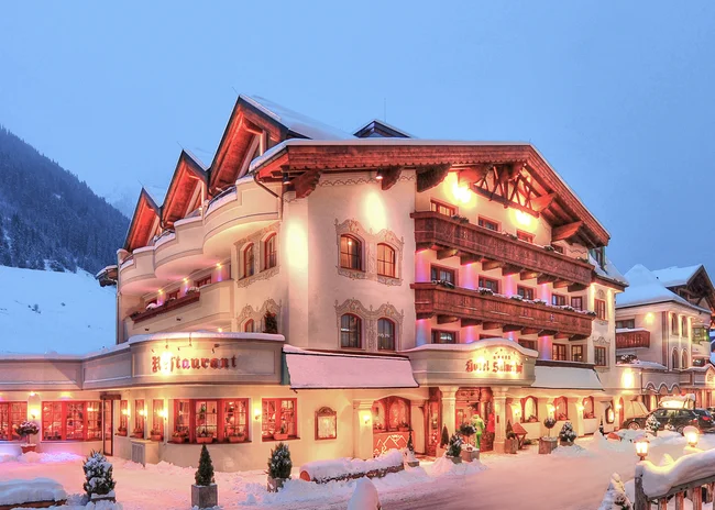 Der Salnerhof – das Hotel in Ischgl Beleuchtetes Hotel in verschneiter Berglandschaft bei Dämmerung