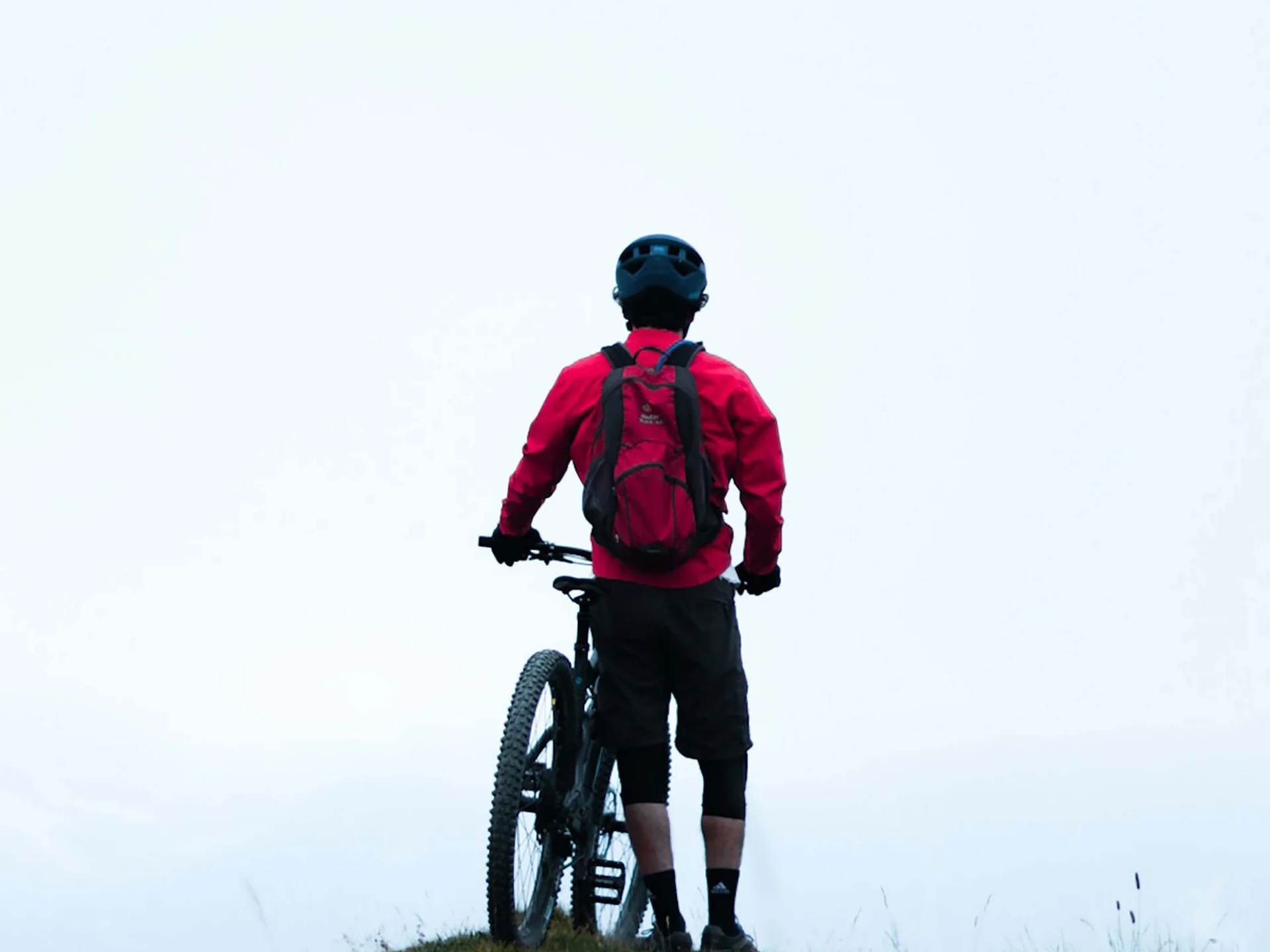 Pictures from Hotel Salnerhof Mountain biker with red backpack standing on hill with bike