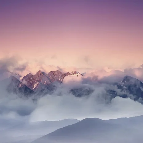 Ihre Anreise zum Salnerhof in Ischgl Berggipfel, die von Wolken umgeben sind bei rosa und violettem Himmel