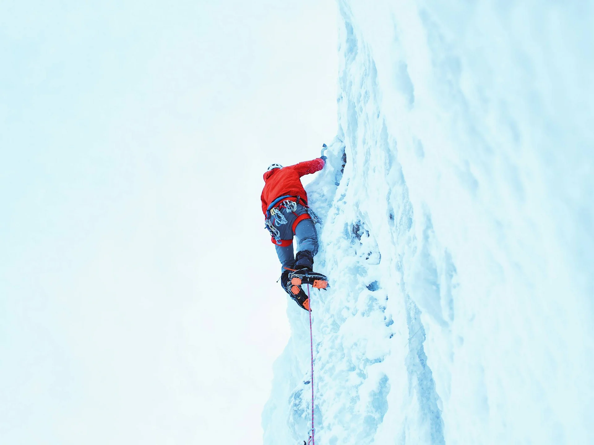 Die Bilder aus dem Hotel Salnerhof Eiskletterer in roter Jacke klettert an steiler Eiswand mit Seilsicherung