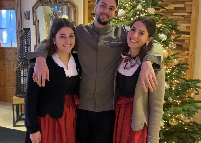 Das Salnerhof-Team | Die Gesichter hinter dem Hotel Drei Personen in traditioneller Kleidung vor einem geschmückten Weihnachtsbaum