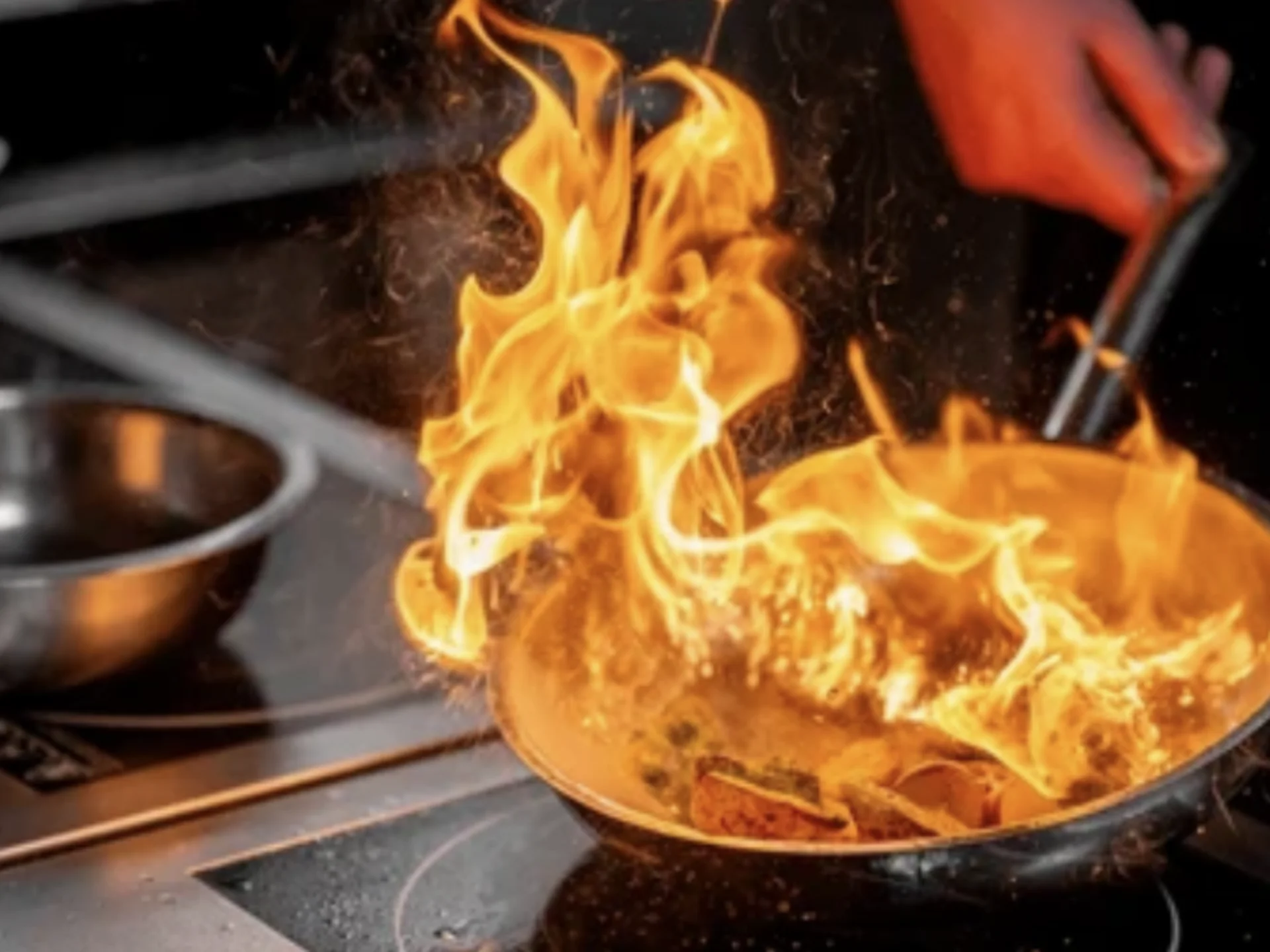Die Bilder aus dem Hotel Salnerhof Flammen schlagen aus einer Pfanne beim Kochen auf einem Herd