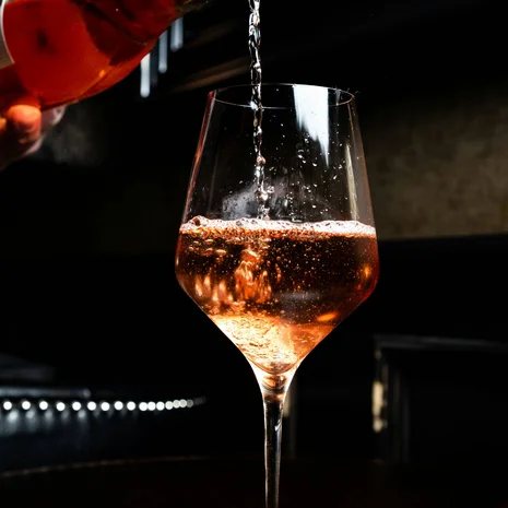 Geschmack Roséwein wird aus einer Flasche in ein Weinglas eingeschenkt