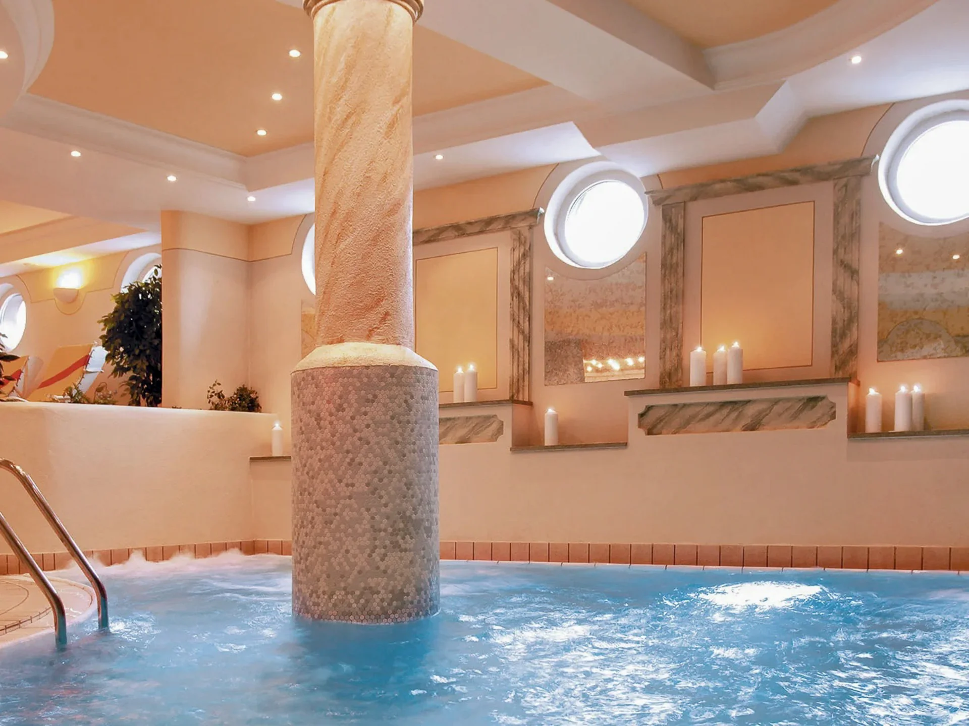 Die Bilder aus dem Hotel Salnerhof Innenpool mit Säulen, Kerzen und runden Fenstern in einem Spa-Bereich