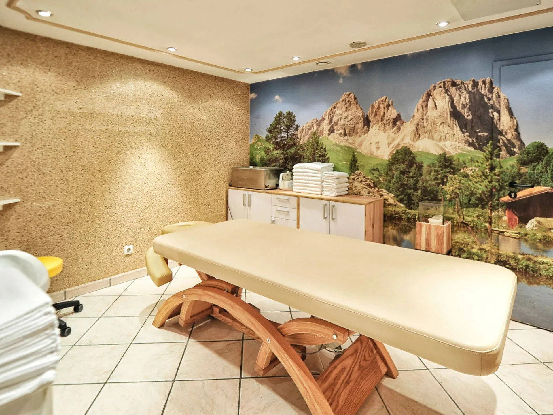 Die Bilder aus dem Hotel Salnerhof Massageliege in hellem Raum mit Berglandschaftswandbild und Handtüchern