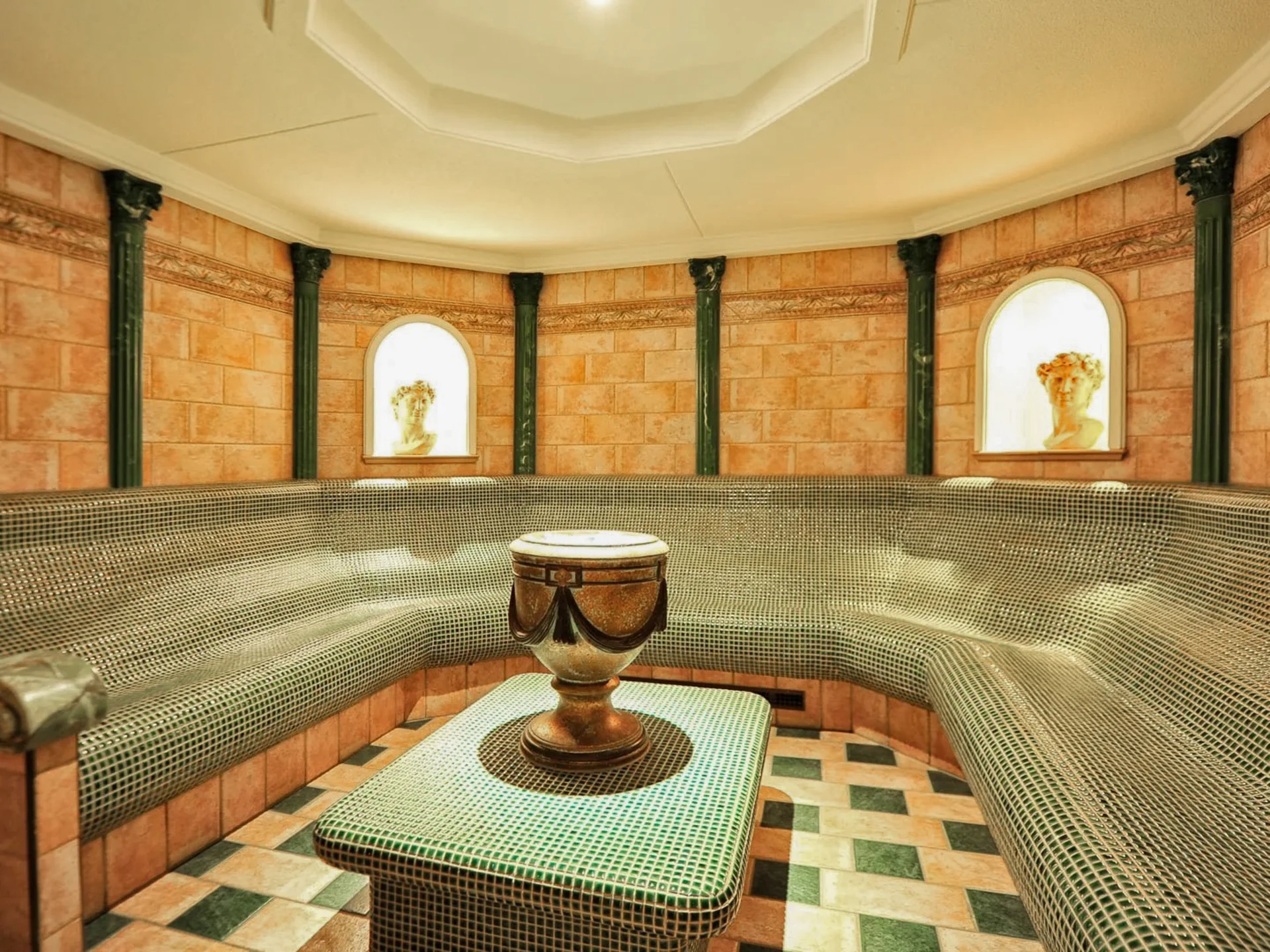 Die Bilder aus dem Hotel Salnerhof Runder Wellnessraum mit Mosaik-Sitzbank und antiken Skulpturen in Nischen