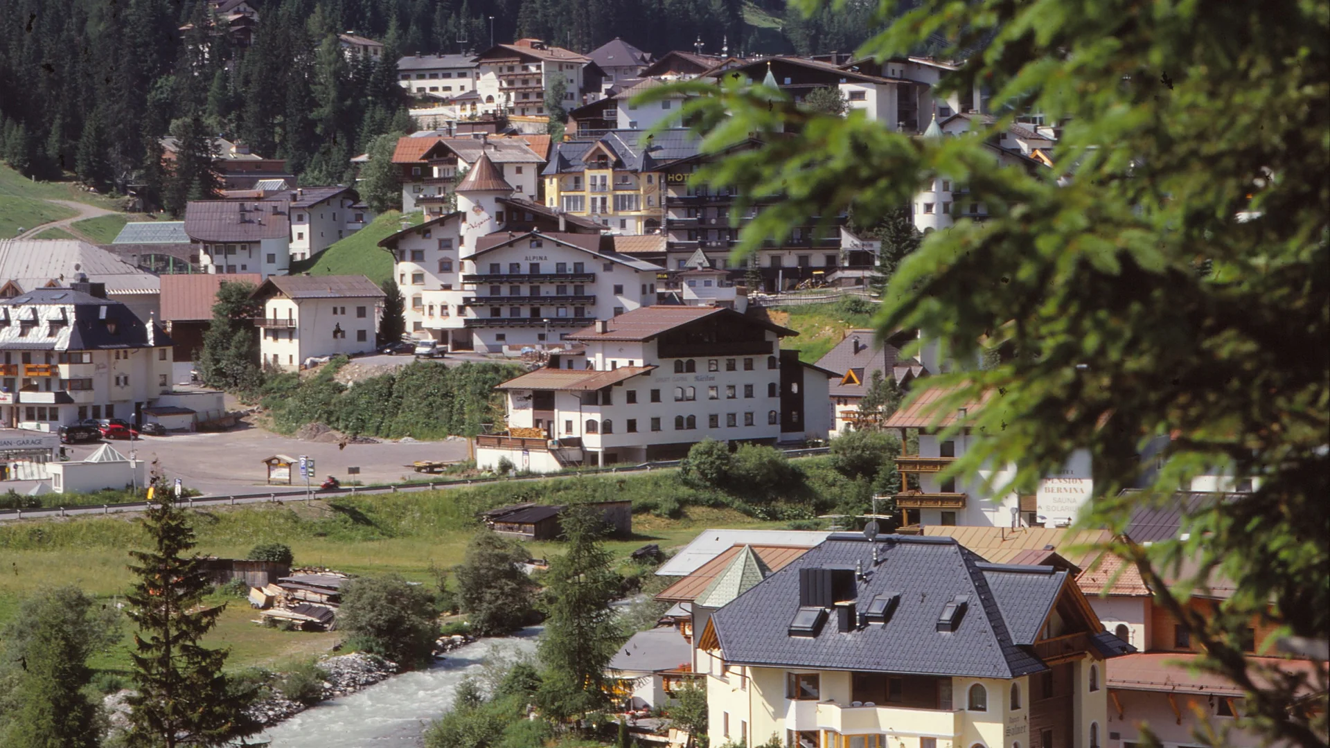 Die Geschichte des Salnerhofs Blick auf ein Dorf mit Fluss, Häusern und Wald im Hintergrund