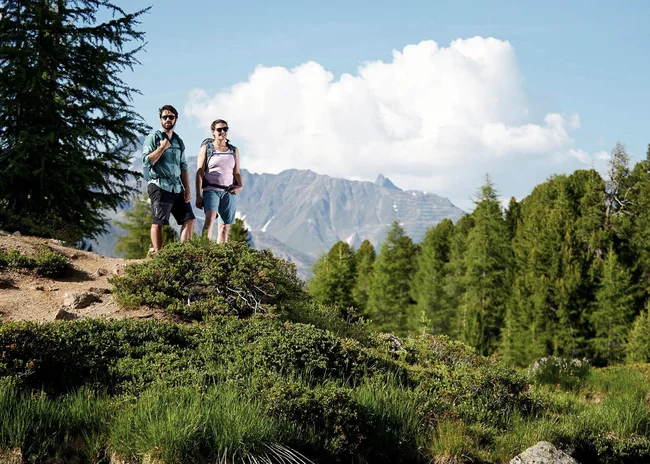 Ihr Sommer im Paznaun im Wander- und Bike-Hotel in Ischgl Zwei Wanderer auf einem Pfad mit Bergen und Bäumen im Hintergrund