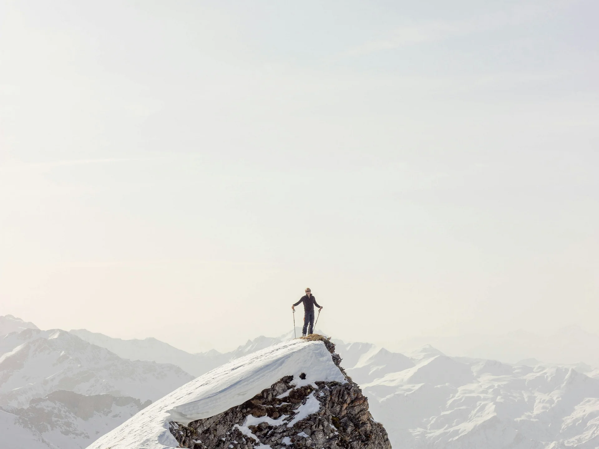 Die Bilder aus dem Hotel Salnerhof Person steht mit Skistöcken auf schneebedecktem Berggipfel mit Bergpanorama