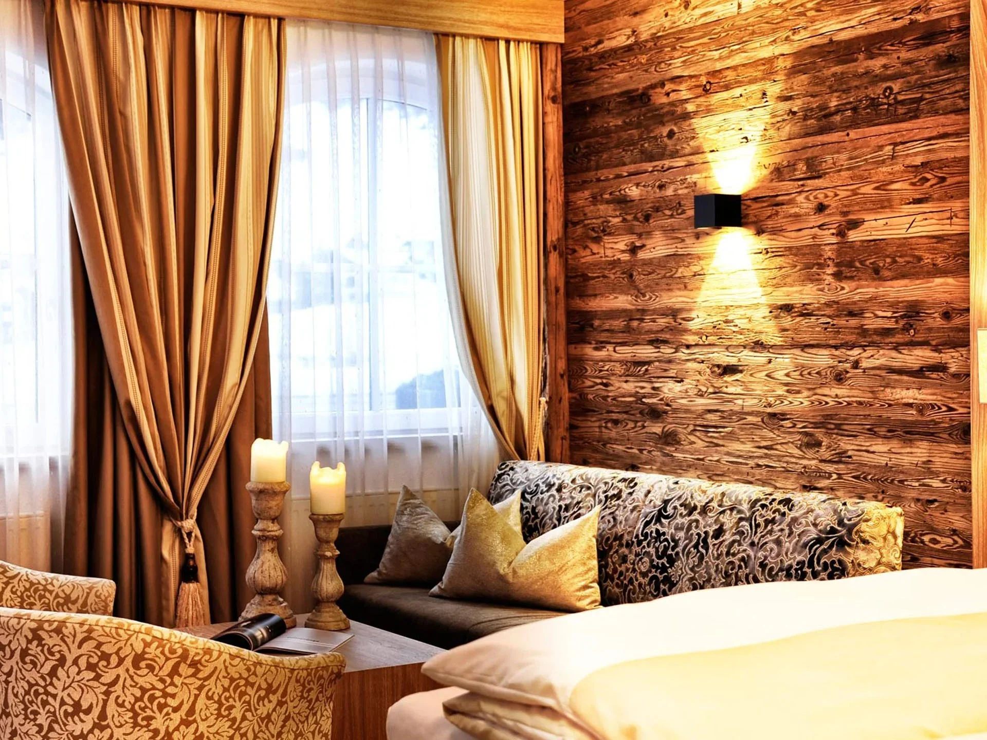 Die Bilder aus dem Hotel Salnerhof Gemütliches Hotelzimmer mit Holzverkleidung, Sofa, Sesseln und Kerzen