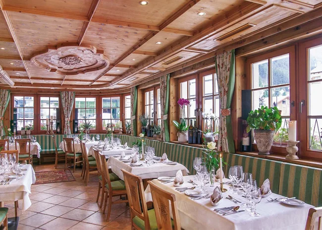 Ihr liebstes Restaurant in Ischgl Gemütlicher Restaurantbereich mit Holzmöbeln und eingedeckten Tischen