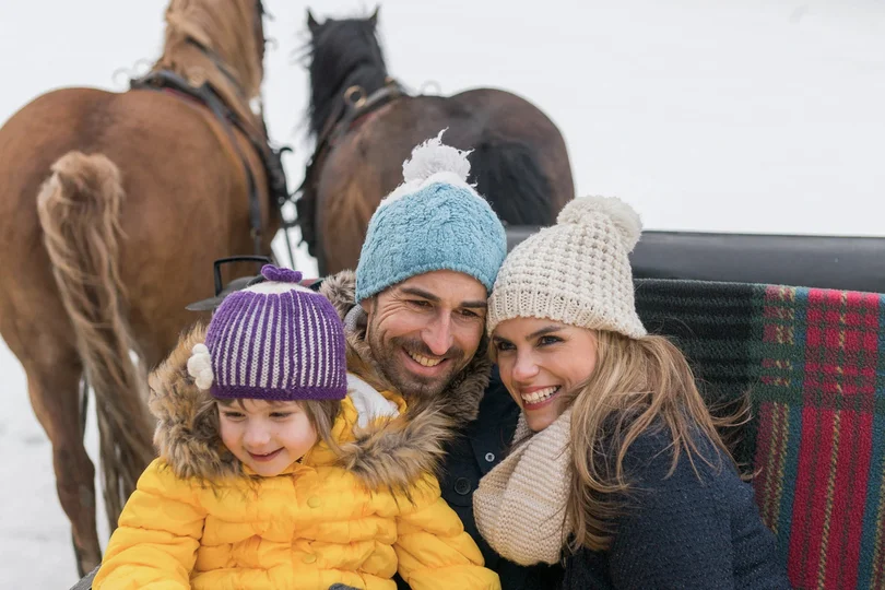 Ihr Skihotel in Ischgl Glückliche Familie mit Kind bei Kutschfahrt im Winter mit Pferden