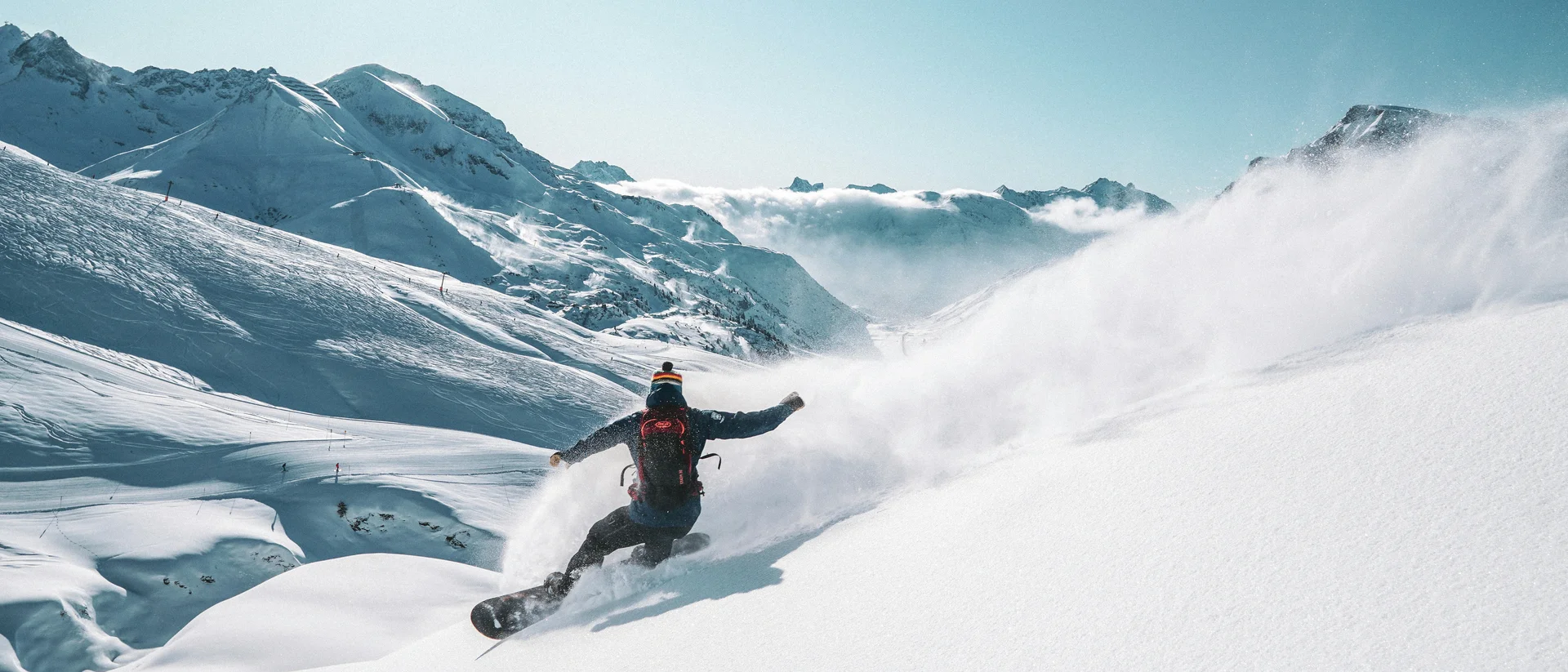 Ihr Skihotel in Ischgl Snowboarder fährt bei sonnigem Wetter auf verschneitem Berghang