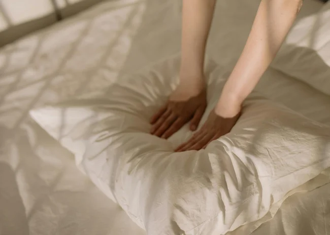 Kellner mit Inkasso Hände drücken ein weiches, weißes Kissen auf einem Bett