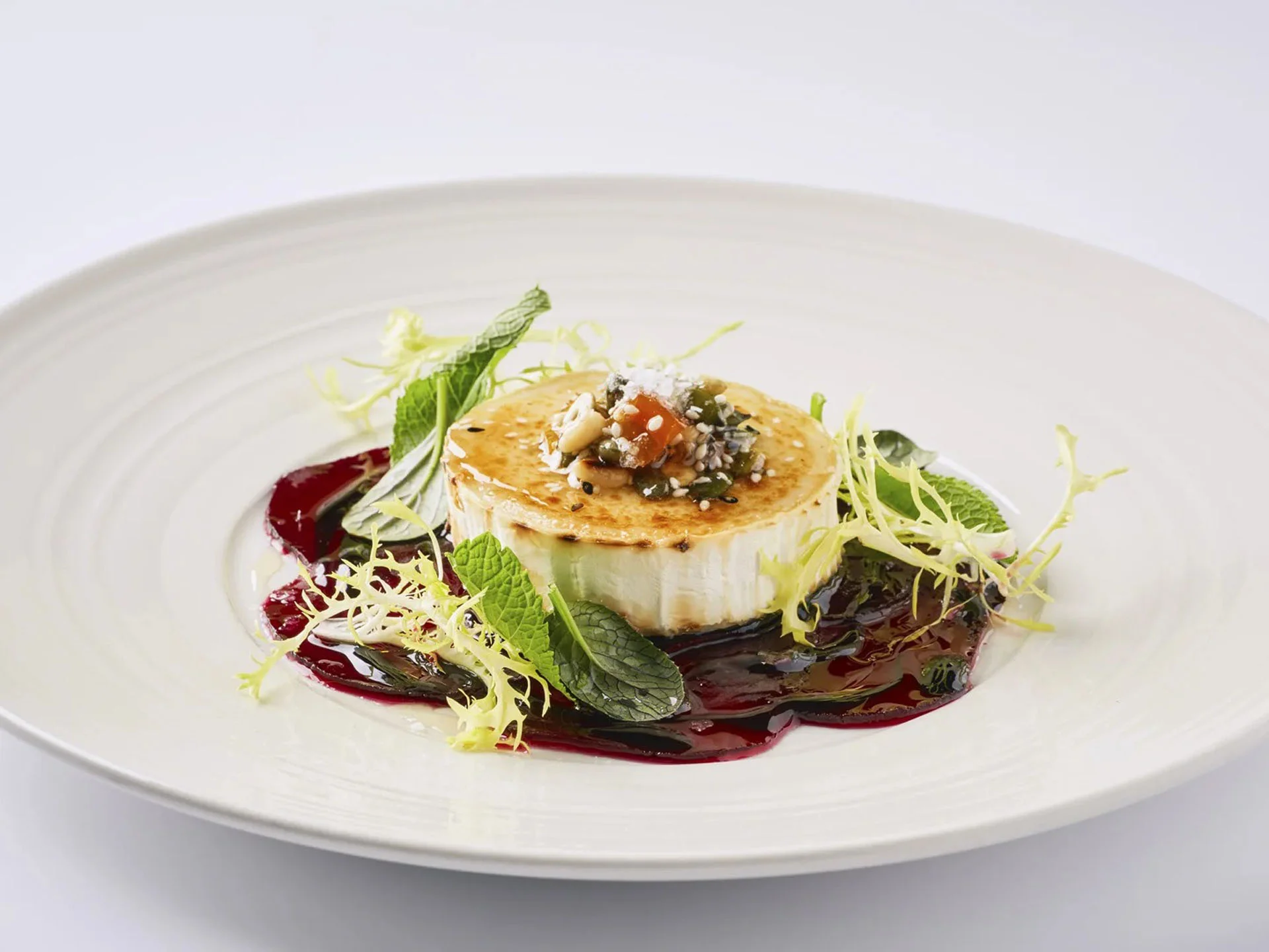 Die Bilder aus dem Hotel Salnerhof Kunstvoll angerichteter Ziegenkäse mit Beeren-Soße und frischen Kräutern auf weißem Teller