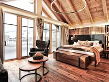 Was erwarten Sie von einer Bar in Ischgl? Gemütliches Schlafzimmer mit Holzbalkendecke und Blick auf verschneite Landschaft